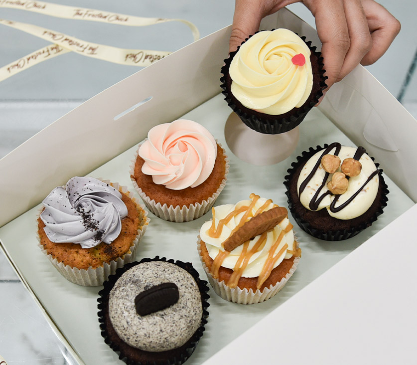Staff placing cupcake into assorted cupcakes box