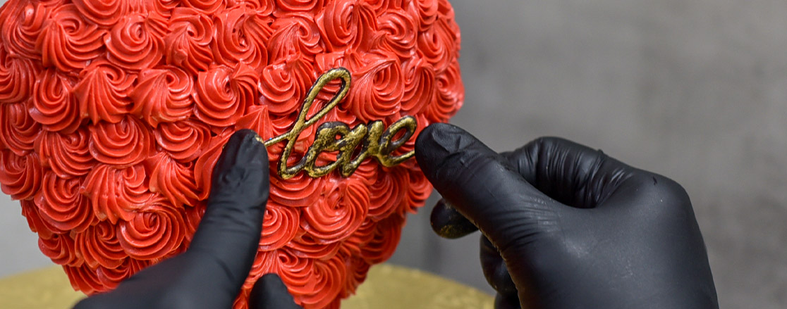 Cake decorator decorating 3d heart shape cake