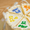 Close-up of Multi Birthdate Cake slices with coloured dates and satin bows